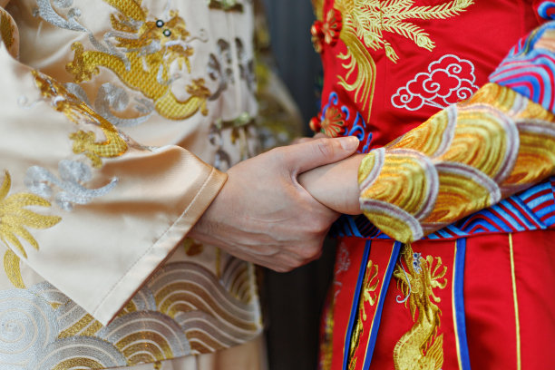 亚洲华人婚礼的新人手牵着手，穿着传统的中国服装。图片下载