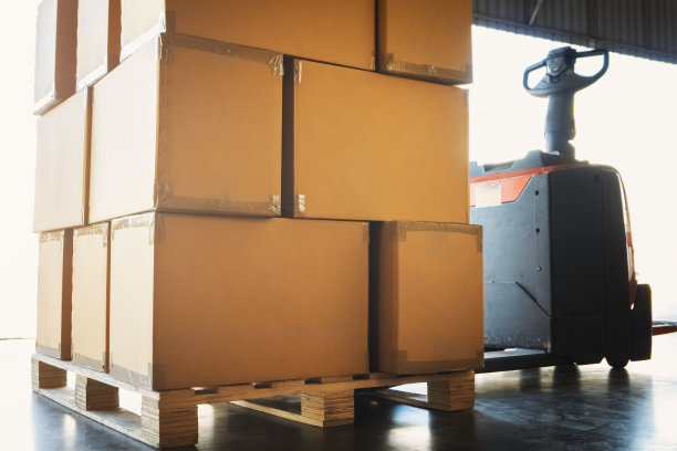 用电动叉车将包装盒堆叠在托盘上。纸箱，硬纸板箱。装运货物。船舶供应，仓储物流。图片下载