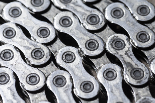 极端特写的闪亮肮脏油腻的自行车链条作为金属自行车设备的一部分在石质背景与对比细节图片下载