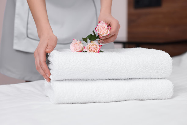 客房服务员将鲜花放在酒店房间的新毛巾上，特写图片下载