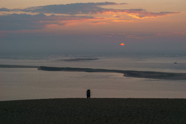 在法国新阿基坦，阿卡康的皮拉特沙丘，一对夫妇站在日落前的剪影图片下载