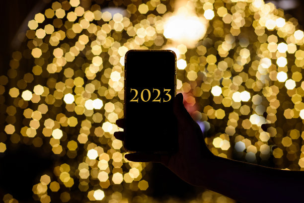 女性手持智能手机，屏幕上显示2023。新年快乐。图片下载