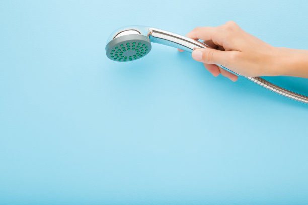 年轻的成年女子手拿淋浴头在浅蓝色的墙壁背景。柔和的颜色。特写镜头。清洗的概念。文本的空白位置。自顶向下视图。图片下载