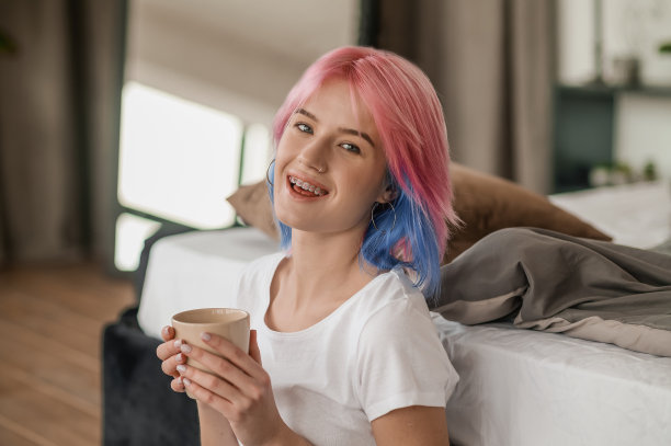 可爱的粉红色头发的女孩享受她的咖啡休息室内图片下载