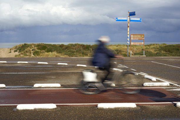 荷兰一位骑自行车的老人在运动。骑自行车的老人在雨天骑自行车。沿途的路标。荷兰，泽兰，布鲁沃斯丹。图片下载