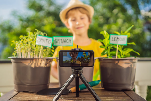 这个男孩在他的阳台上录制了一个关于园艺的视频博客。儿童的自然发展图片下载