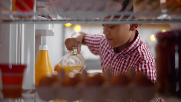 微笑的非洲裔美国孩子从冰箱里拿橙汁图片下载