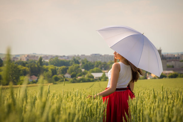 漂亮的白人女性在绿色的草地上撑着伞图片下载