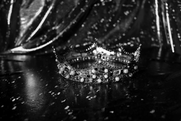 皇家皇冠与珍贵的宝石在红色豪华闪光织物背景。黑色和白色。图片下载