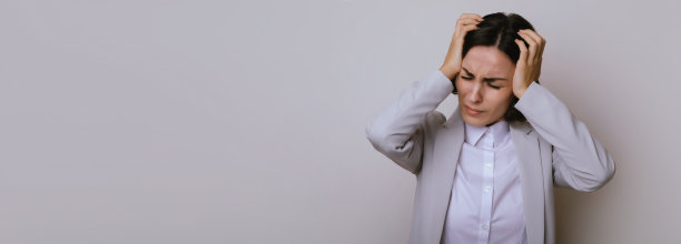 年轻的商业女性孤立在灰色的背景是遭受严重的头痛，绝望和压力，因为疼痛和偏头痛后麻烦的工作图片下载