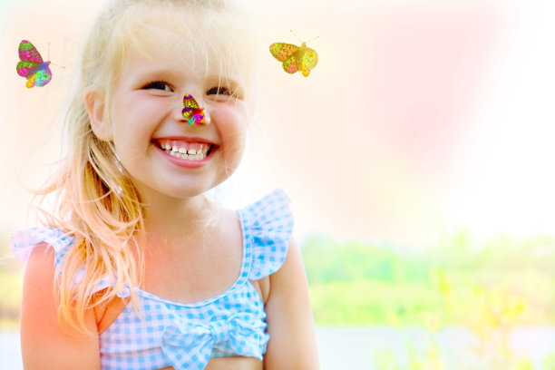 笑着蹒跚学步的漂亮女孩与蝴蝶的肖像。海滩上的快乐时光。快乐的童年和自由的概念图片下载