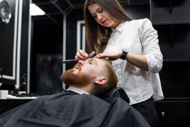 发型师女孩剃须男子在理发店图片下载