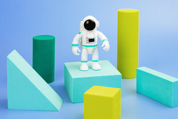 蓝色背景上的穿着太空服的宇航员塑料雕像和几何形状图片下载