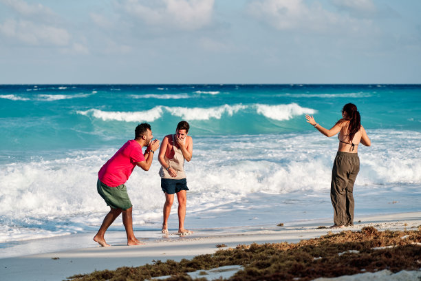 一组三人，两男一女，在坎昆海滩度假时分享和玩耍图片下载