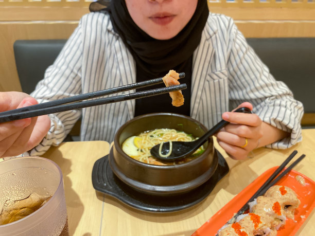 年轻的戴头巾的女人吃日本食物图片下载