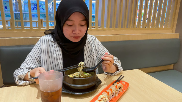 年轻的戴头巾的女人吃日本食物图片下载