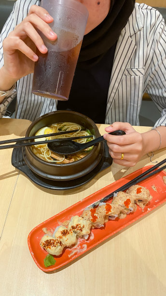 年轻的戴头巾的女人吃日本食物图片下载