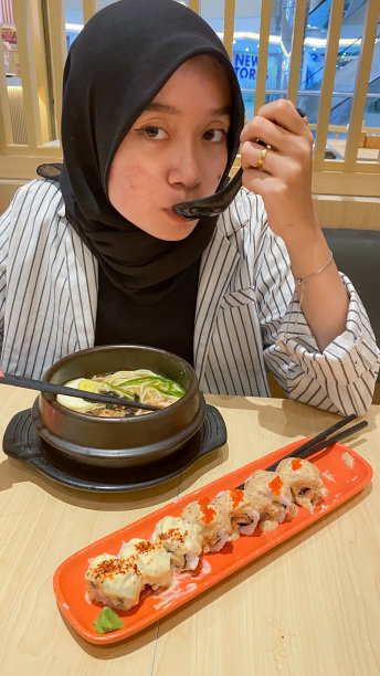 年轻的戴头巾的女人吃日本食物图片下载