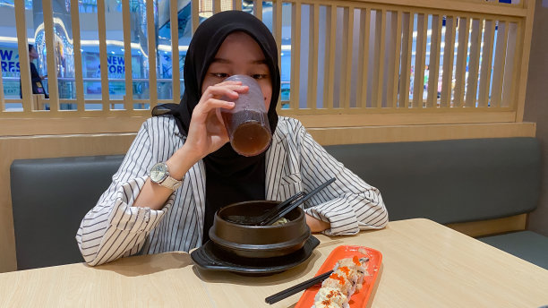 年轻的戴头巾的女人吃日本食物图片下载