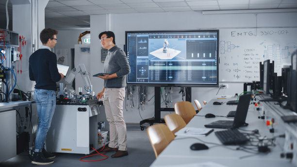 未来机器人工程师团队致力于机器人手臂设计，并讨论未来设备的技术能力。学生使用平板电脑。数字技术与成功概念。图片下载