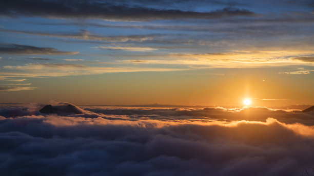 夕阳在高山上的云层上，伴随着阳光图片下载