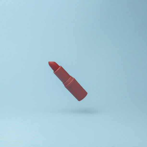 红色口红管飞行在反重力的蓝色背景与阴影。悬浮在空中的物体。美与时尚理念。创意最小布局图片下载