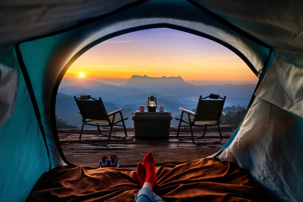 在山中，一个女人在带睡袋的帐篷里盘腿在毯子上。从内部看Doi luang chiang dao山。图片下载