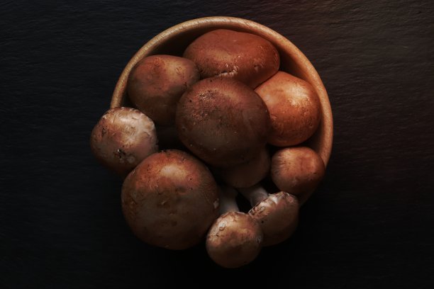 照片的棕色巴黎蘑菇在一个木碗上的石板为食物背景图片下载