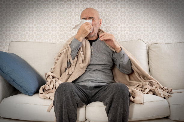 家里有毯子的沙发上，老病人对着餐巾打喷嚏。图片下载