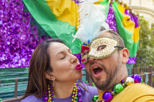 快乐的拉丁游客朋友/异性恋情侣在新奥尔良庆祝狂欢节，戴着项链和面具自拍。图片下载