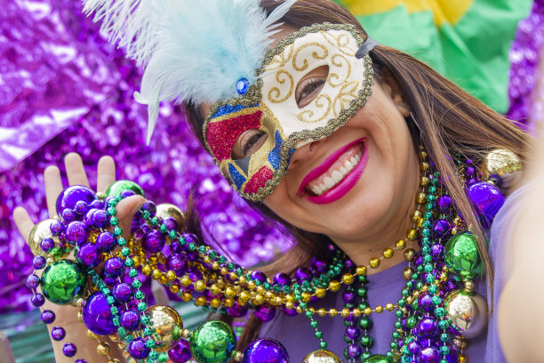 一名年轻的拉丁女游客，戴着面具，穿着服装，戴着项链，在新奥尔良的街道上庆祝狂欢节，同时用她的手机自拍。图片下载