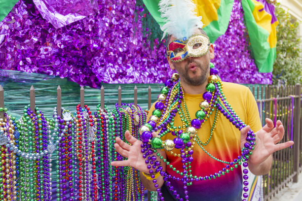 一位年轻的拉丁男性游客，戴着面具，穿着服装，戴着项链，在新奥尔良的街道上庆祝狂欢节。图片下载