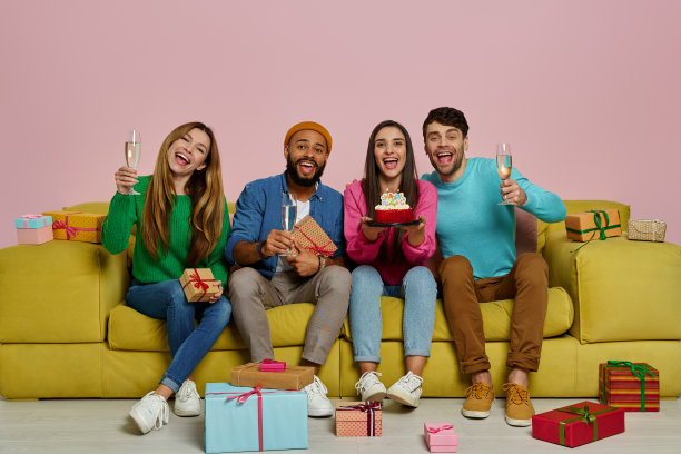 年轻人坐在沙发上庆祝生日，背景是粉红色的图片下载
