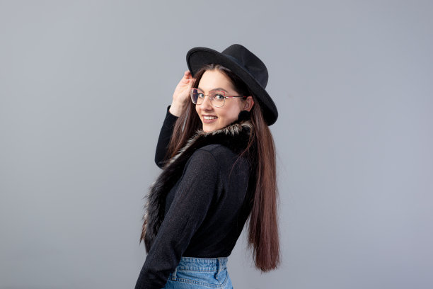 一个性感的女人的肖像长发和黑色的帽子在她的头上孤立在灰色的背景图片下载