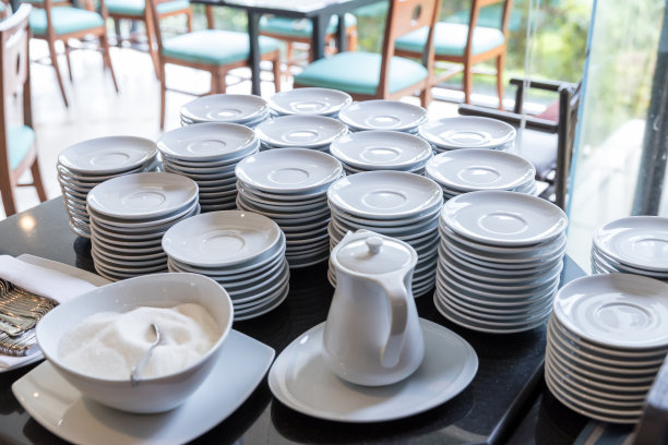 吧台和干净的盘子准备工作。旅馆里堆在一起的一组白色盘子。酒店会议中心咖啡。成堆的空盘子。图片下载