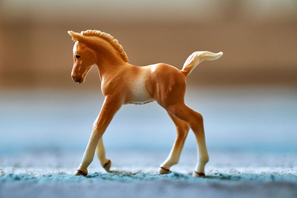 特写镜头一个白色和金色的马驹玩具在地毯上的地面上模糊的背景图片下载