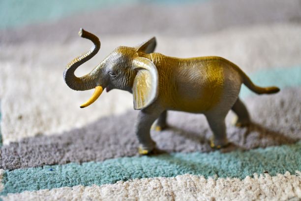 一个棕色大象玩具的特写镜头在地毯上明亮的阳光与模糊的背景图片下载