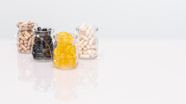 不同种类的维生素胶囊装在玻璃罐里，背景明亮图片下载