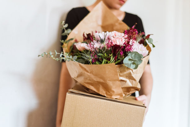 一个女人拿着一大束花放在一个纸板箱里图片下载