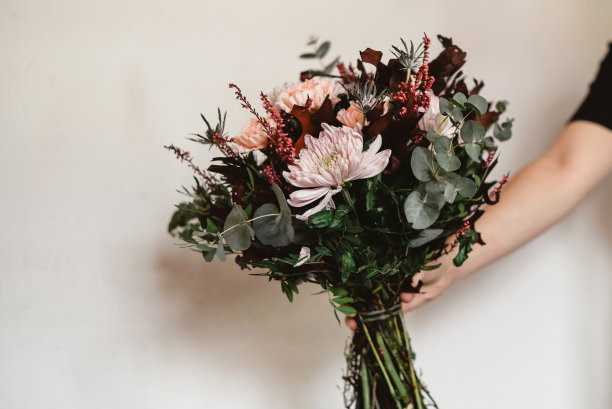 手捧一束粉红色和紫红色的花。图片下载