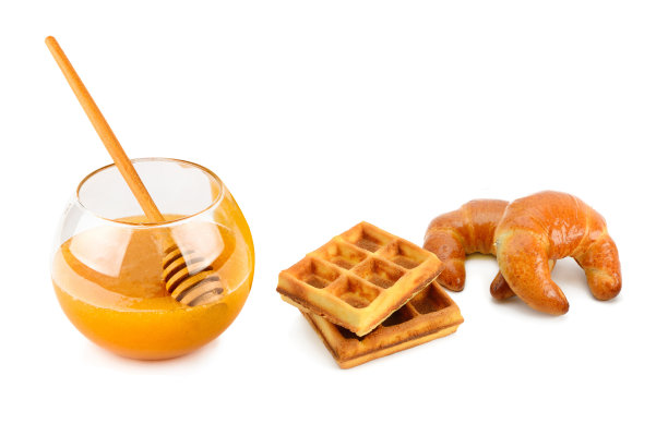 蜂蜜，羊角面包和华夫饼单独放在白色蛋糕上。图片下载