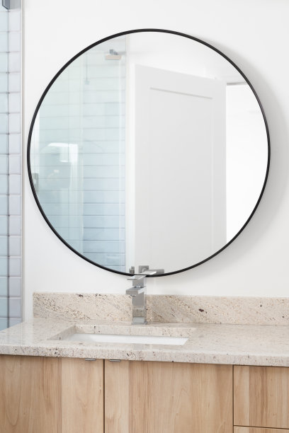 一间带木柜子和圆形镜子的浴室。图片下载