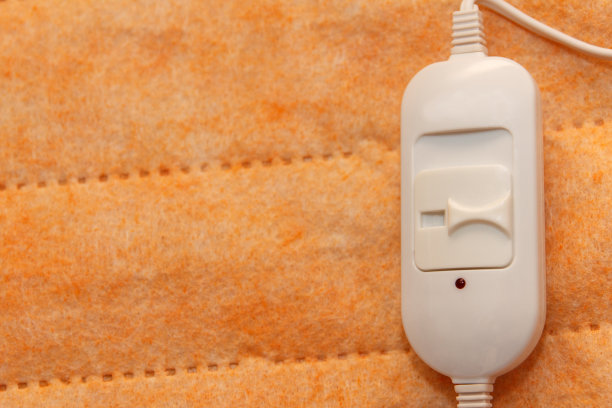 一个温暖美丽的橙色新电子床单，躺在组装，并在床单上躺着一个温度开关。在寒冷的季节，这是一种快速而经济的取暖方式图片下载