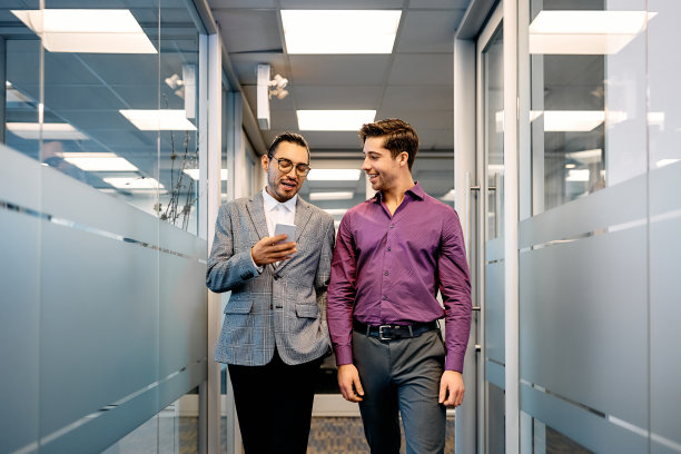 年轻的商人在办公室走廊上使用手机。图片下载