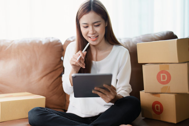 开始创业的独立年轻亚洲女性在线卖家使用平板电脑和订单包装产品交付给客户。中小企业交付概念图片下载