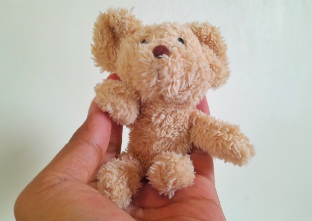 一个亚洲男人手拿一个可爱的熊娃娃图片下载