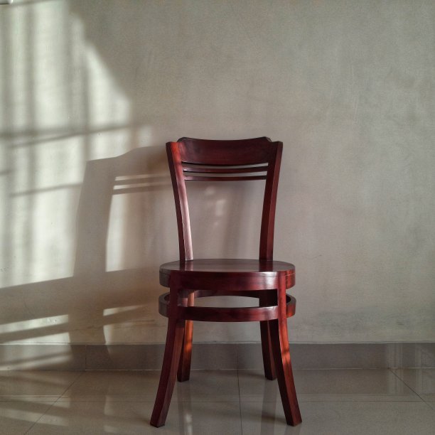 棕色的木椅站在白色的墙与阴影从阳光照耀图片下载