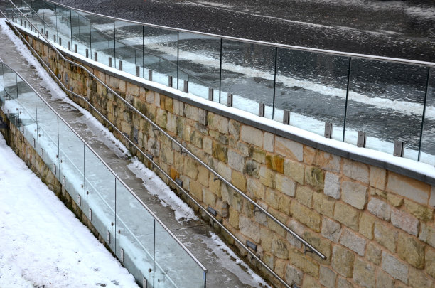 一幢豪华住宅的栏杆，由灰色金属不锈钢镶板固定的玻璃板组成。乳白色的磨砂玻璃屏障给人一种通风的印象。抛光金属盖，雪图片下载