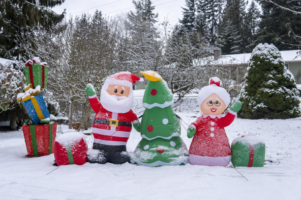 雪地里有圣诞老人的充气塑像、圣诞树、圣诞老人的妻子和装着礼物的盒子。圣诞和新年假期户外装饰。下雪的冬天图片下载