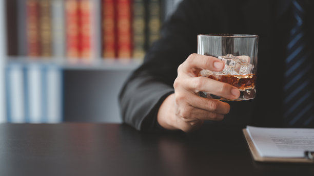 一个律师拿着一杯威士忌，他在他的办公室里，他在为一个客户辩护，他是个律师。法律诉讼概念明确。图片下载
